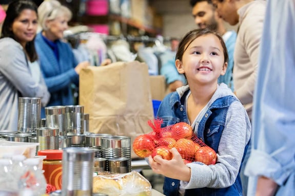 Child donating goods to food bank